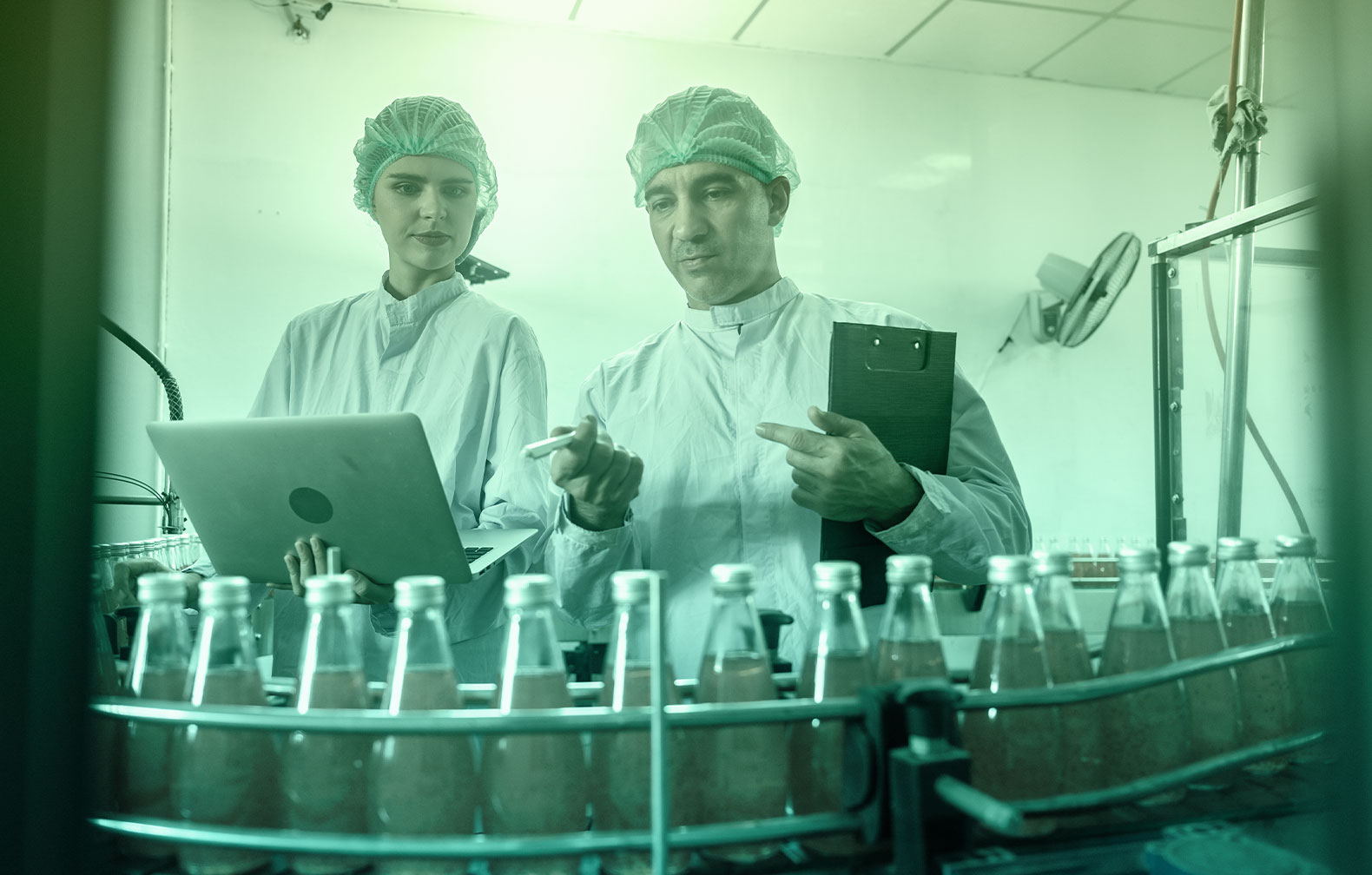 Food technicians annotating observations in CMMS software on a laptop
