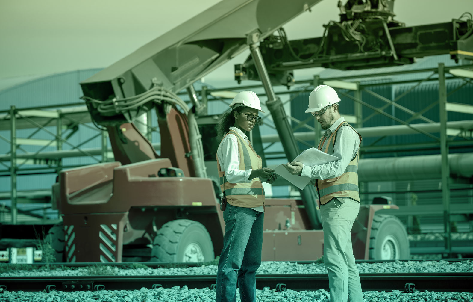 Two maintenance technicians are discussing the maintenance schedule on a paper sheet with a boom forklift in the background