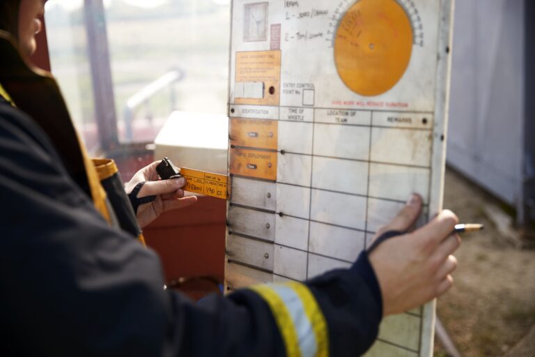 Maintenance technician writing last date of maintenance on a tab to later insert into a board. This is an old way to track maintenance. This is inefficient and dangerous as information can get lost. A CMMS can be tracked from anywhere by the safe authorized users, and information can be obtained in a few clicks making maintenance management easier